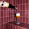 PAIRING versée dans un verre à pied devant un carrelage orange
