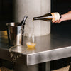 PAIRING versée dans un verre, à côté d'un seau à glace sur un comptoir en métal